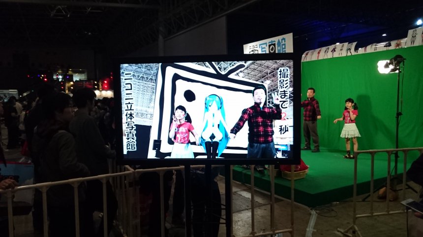 站在绿幕前,和虚拟人物来张合照吧.两父女选择了和初音未来合照.